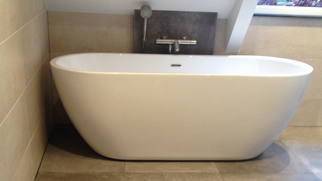 Tegelwerk met beige tegels in een badkamer met vrijstaand bad in Emst